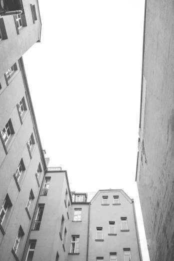 a couple of tall buildings next to each other, a black and white photo, unsplash, minimalism, courtyard, kreuzberg, white space in middle, worm\'s eye view