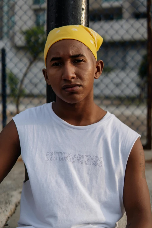 a man sitting on the ground with a tennis racket, trending on unsplash, hyperrealism, gang saints wear yellow bandanas, wearing : tanktop, portrait soft low light, latino