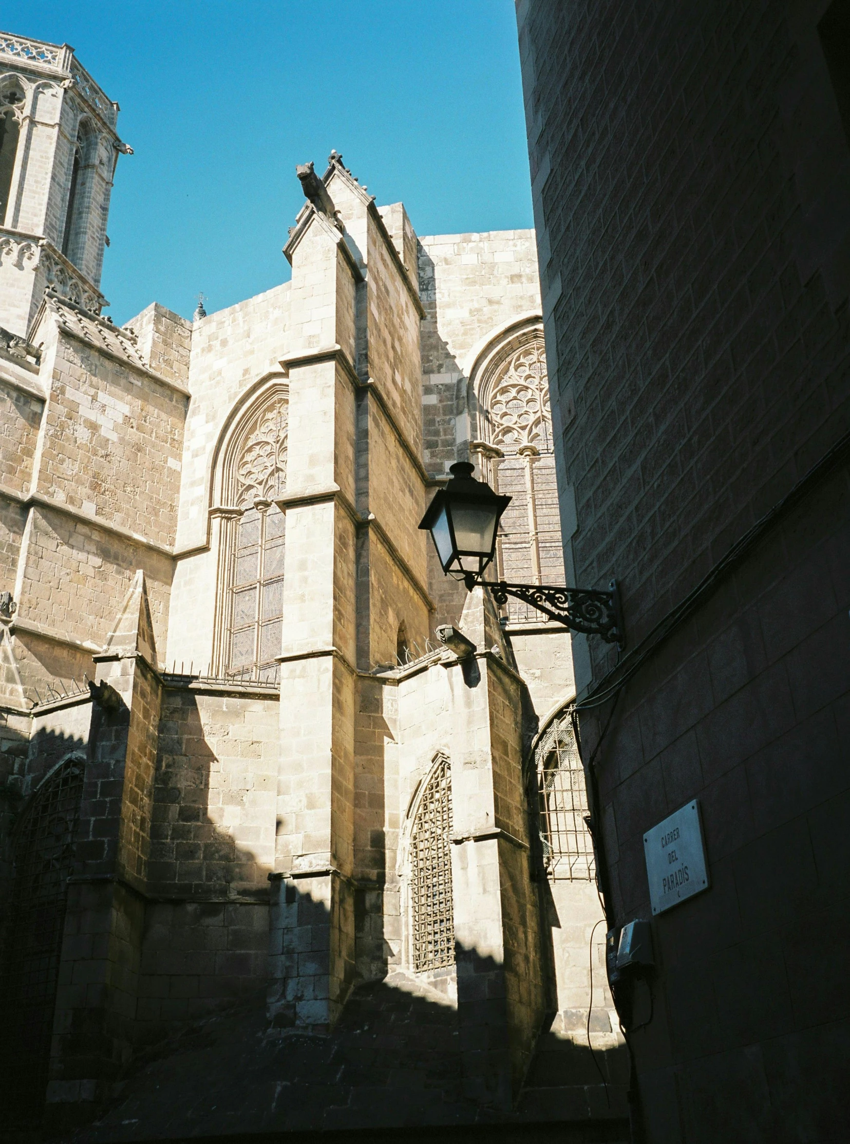 a very tall building with a clock tower in the background, inspired by Modest Urgell, unsplash, romanesque, shady alleys, cathedral of sun, kodak portra, looking around a corner