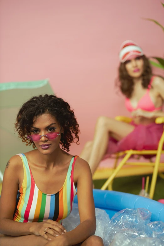 a woman sitting on top of an inflatable pool, inspired by Peter Alexander Hay, trending on pexels, kitsch movement, two models in the frame, colorful striped pavillions, tan complexion, promo still