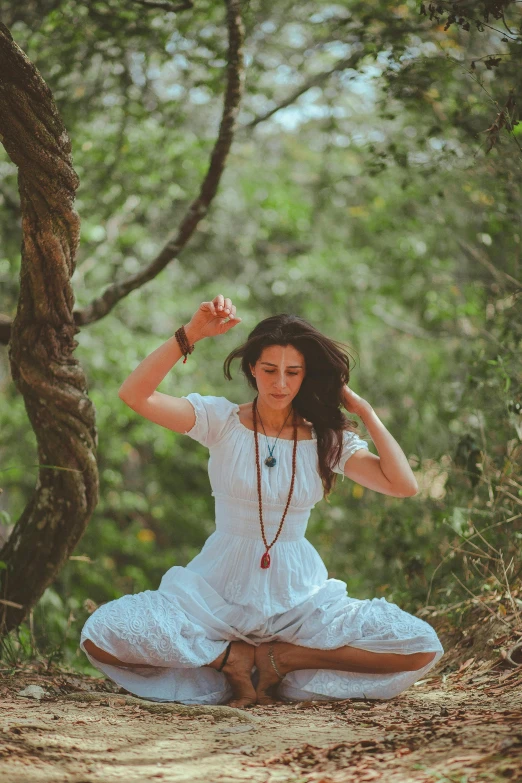 a woman sitting in the middle of a forest, arabesque, kundalini energy, doing a sassy pose, woman with braided brown hair, wearing a white dress