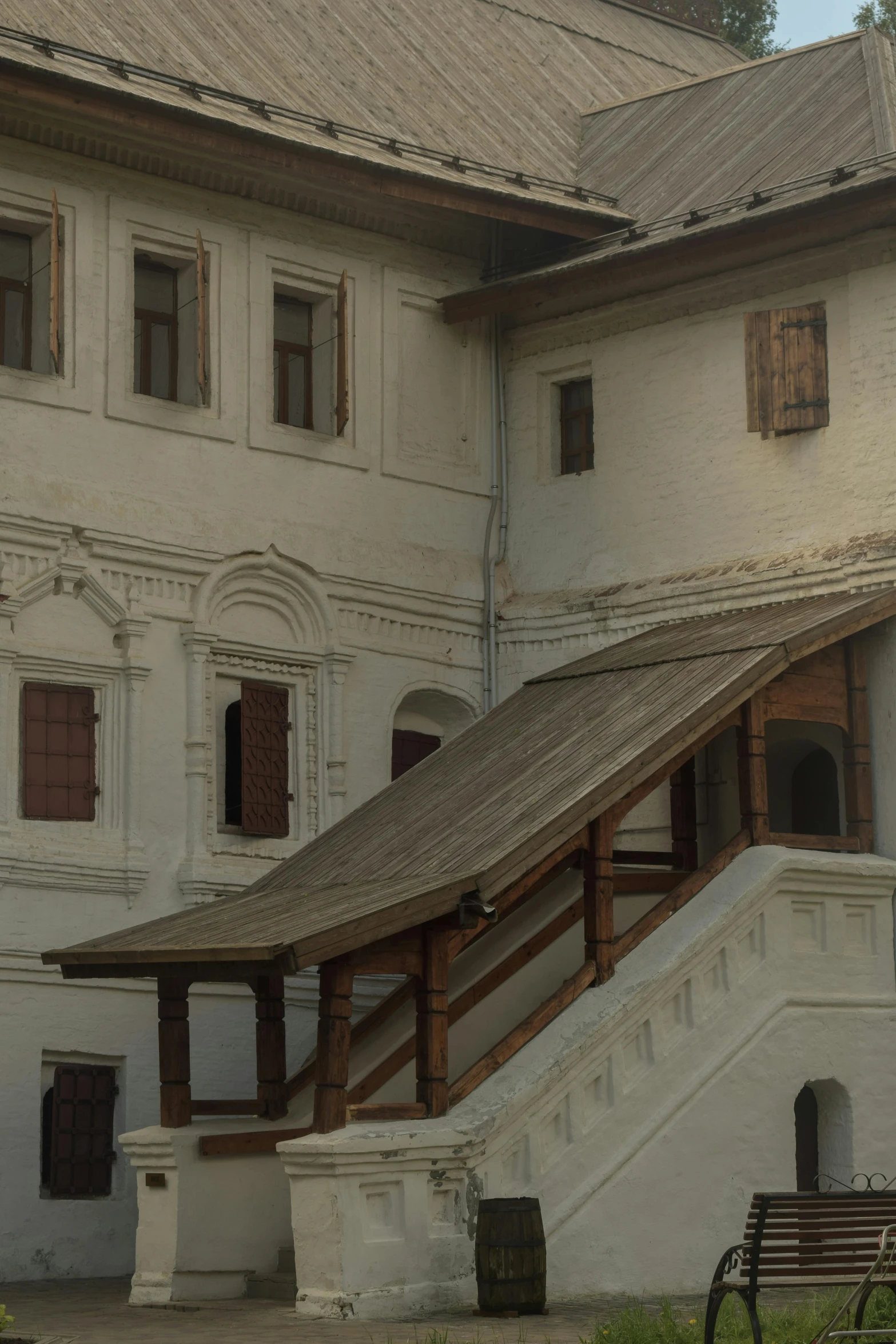 a wooden bench sitting in front of a white building, inspired by Altoon Sultan, renaissance, nepal, 1 staircase, roofs, collapsed ceiling