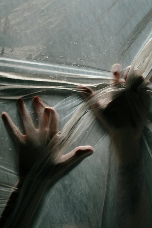 a close up of a person holding an umbrella, an album cover, inspired by Katia Chausheva, pexels contest winner, conceptual art, flowing silk sheets, arachnid, hands shielding face, see through