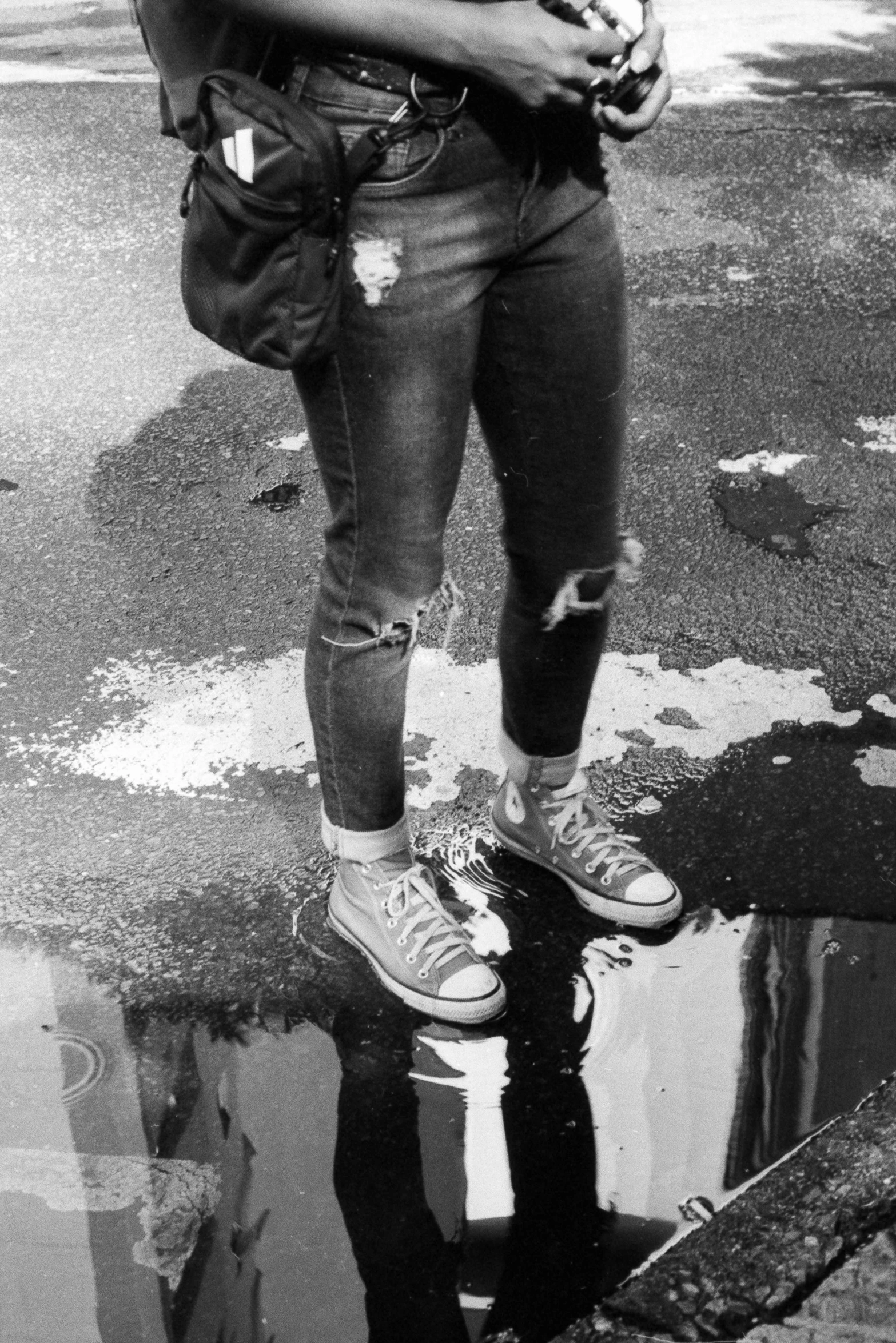 a woman standing next to a puddle of water, inspired by Roy DeCarava, dribble, ( ( ( wearing jeans ) ) ), teenage jughead jones, sneakers, hedi slimane