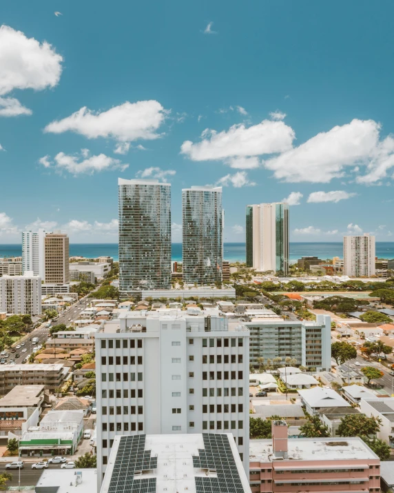 a view of a city from the top of a building, waikiki beach skyline, white building, three towers, apartment