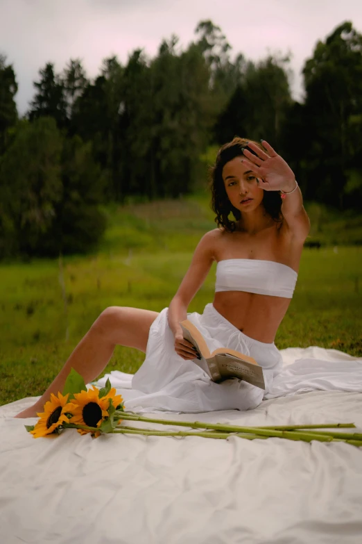 a woman sitting on a blanket reading a book, an album cover, inspired by Konstantin Somov, pexels contest winner, white outfit, bare midriff, sunflowers in the background, 5 0 0 px models