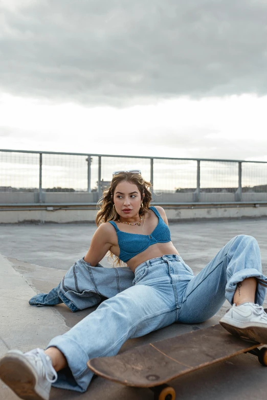 a beautiful young woman sitting on top of a skateboard, an album cover, inspired by Elsa Bleda, trending on pexels, happening, blue pants, portrait sophie mudd, on rooftop, physical : tinyest midriff ever