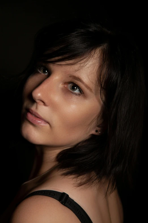 a woman posing for a picture in the dark, an album cover, pexels contest winner, photorealism, diffused natural skin glow, dark hair, studio backlight, taken in the late 2010s