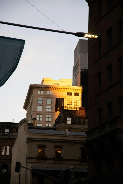 a street light with a building in the background, golden hour in manhattan, james turrell building, hiding in the rooftops, central station in sydney