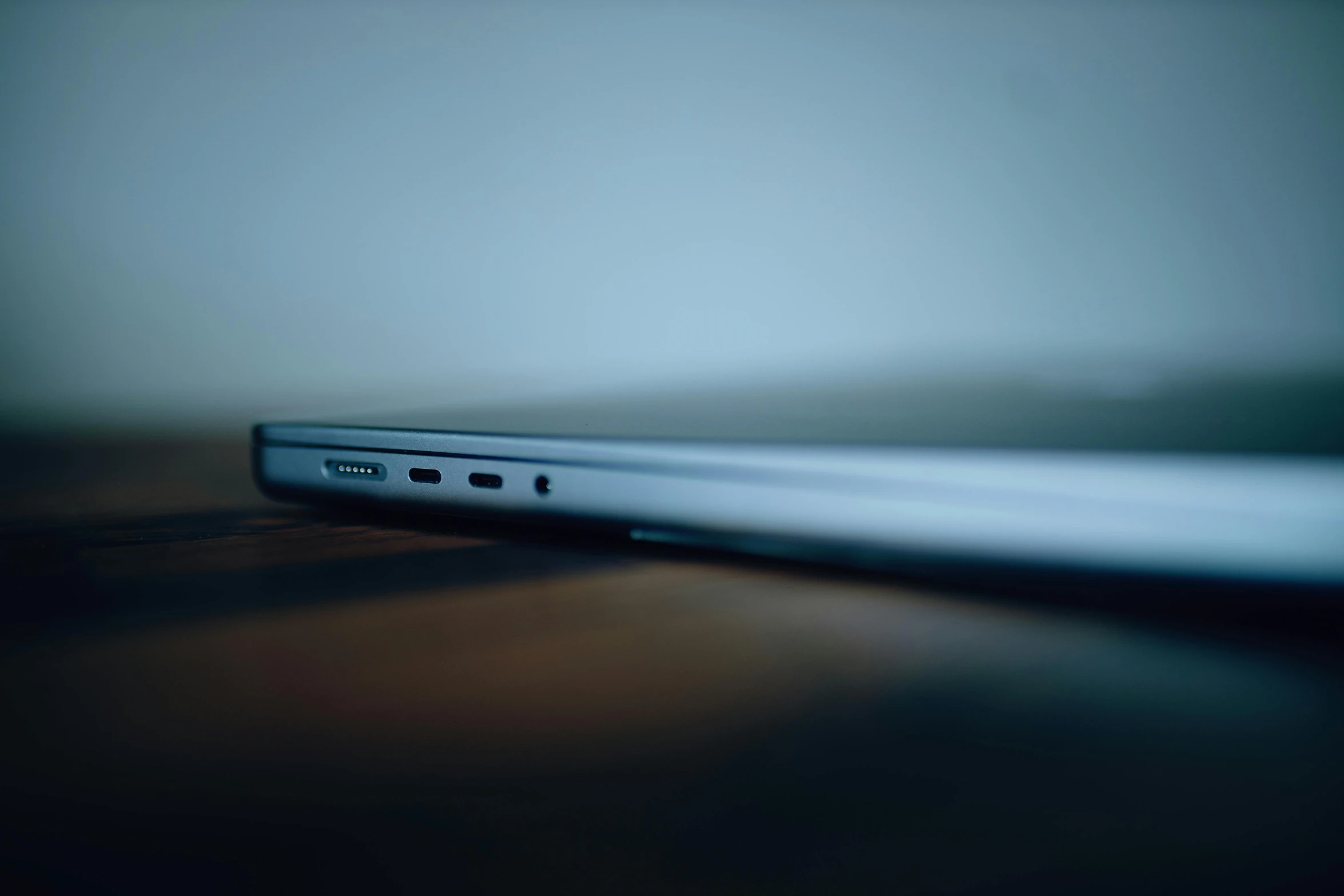 a laptop computer sitting on top of a wooden table, by Ryan Pancoast, unsplash, hyperrealism, profile close-up view, bending down slightly, smooth tiny details, 4 k hd wallpapear