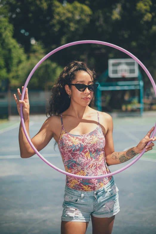 a woman standing on a tennis court holding a hula hoop, pexels contest winner, portrait of vanessa morgan, wearing a tanktop, woman with rose tinted glasses, mixed race