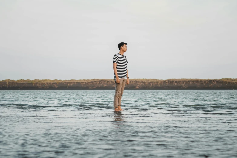 a woman standing in the middle of a body of water, by Nina Hamnett, unsplash, wearing stripe shirt, handsome man, li zixin, full length portrait