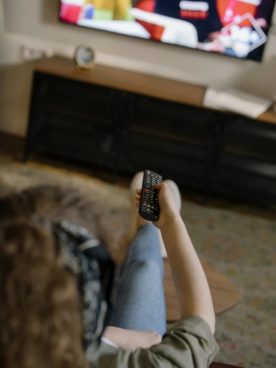 a woman sitting on a couch holding a remote control, by Adam Marczyński, trending on pexels, happening, tv frame, lying down, gif, promo image