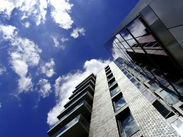 a tall building with lots of windows and a sky background, unsplash, bauhaus, big blue sky, ten flats, . dramatic angle, view from the streets