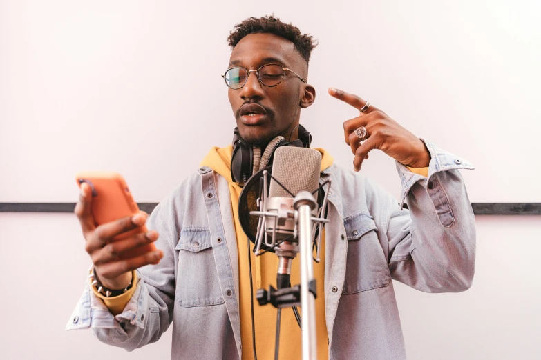 a man standing in front of a microphone holding a cell phone, trending on pexels, ashteroth, mkbhd, instagram influencer, studio picture