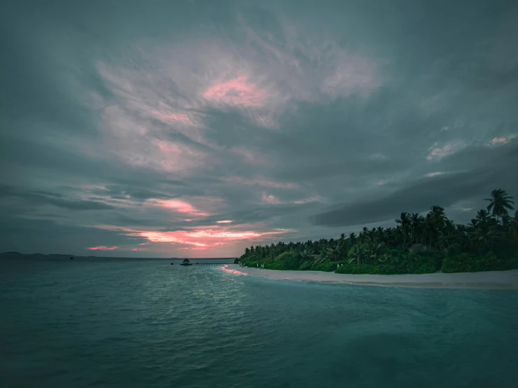 a small island in the middle of a body of water, a picture, unsplash contest winner, hurufiyya, pink and grey clouds, maldives in background, which shows a beach at sunset, gloomy skies