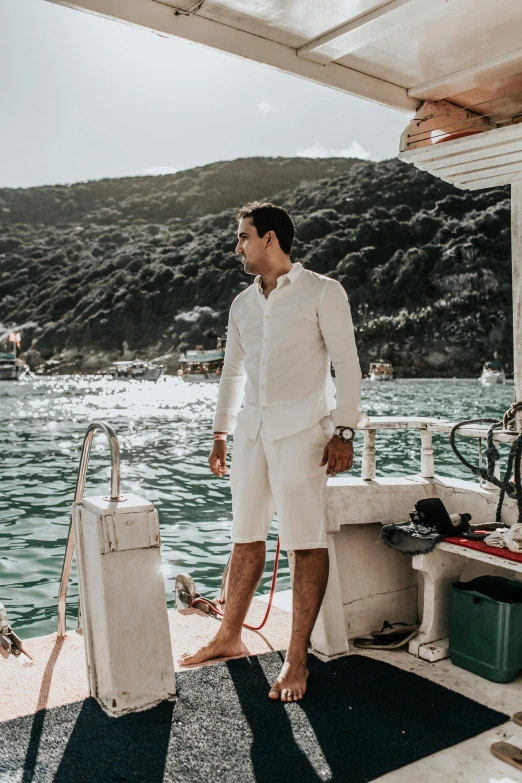 a man standing on the deck of a boat, inspired by Ramon Pichot, pexels contest winner, white outfit, abel tasman, smart casual, full body photograph