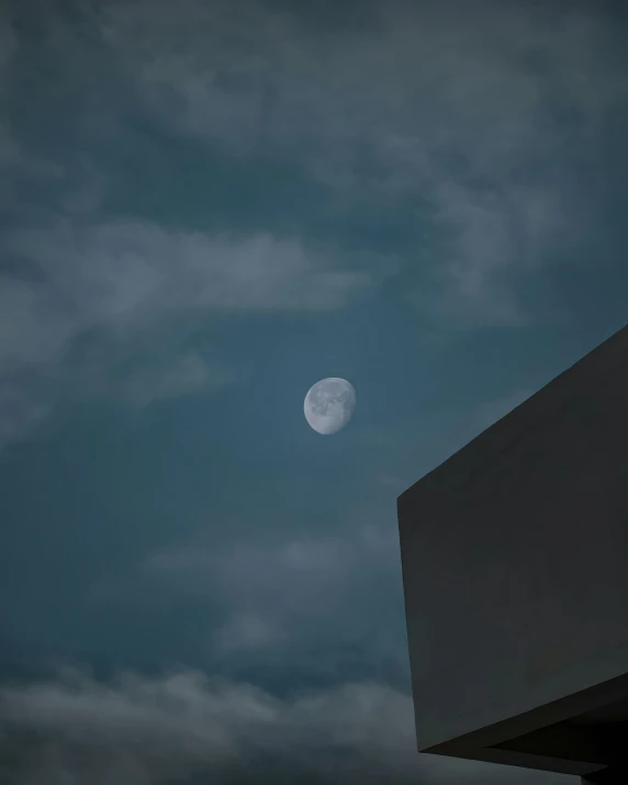 the moon is seen through the clouds above a building, by Cosmo Alexander, unsplash contest winner, postminimalism, ☁🌪🌙👩🏾, moonbow, moonlight grey, minimalist photo