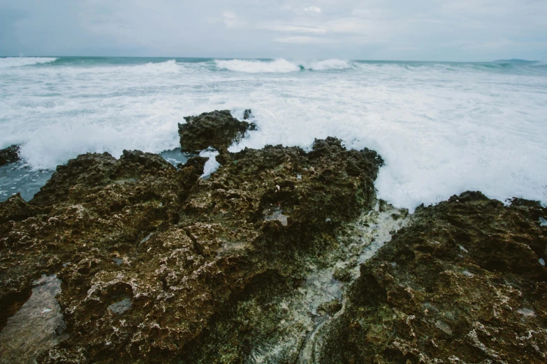 a large body of water sitting on top of a rocky beach, pexels contest winner, mutiversal tsunami, overcast, tropical reef, background image