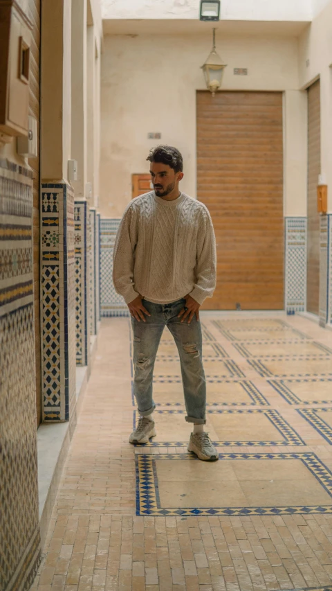 a man standing in a hallway in a building, by Riad Beyrouti, young spanish man, full body 8k, press photos, muted colors. ue 5