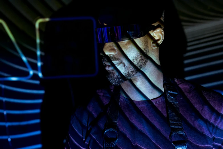 a man holding a cell phone up to his face, a hologram, afrofuturism, wearing vr goggles, out in the dark, wearing space techwear, avatar image