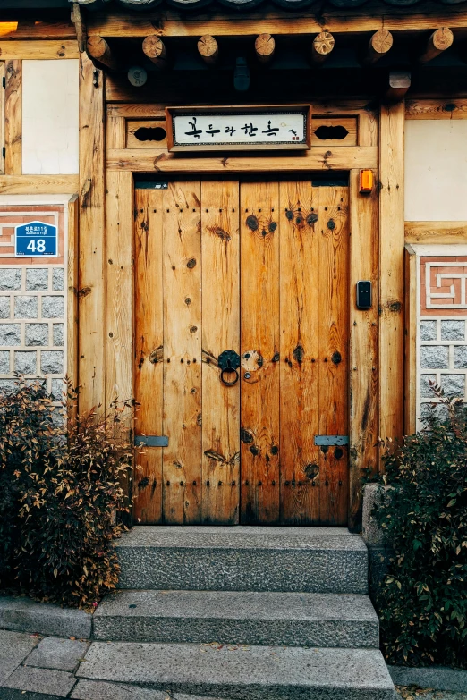 a wooden door sitting on the side of a building, inspired by Kim Myeong-guk, unsplash, square, 1894, exterior, front face