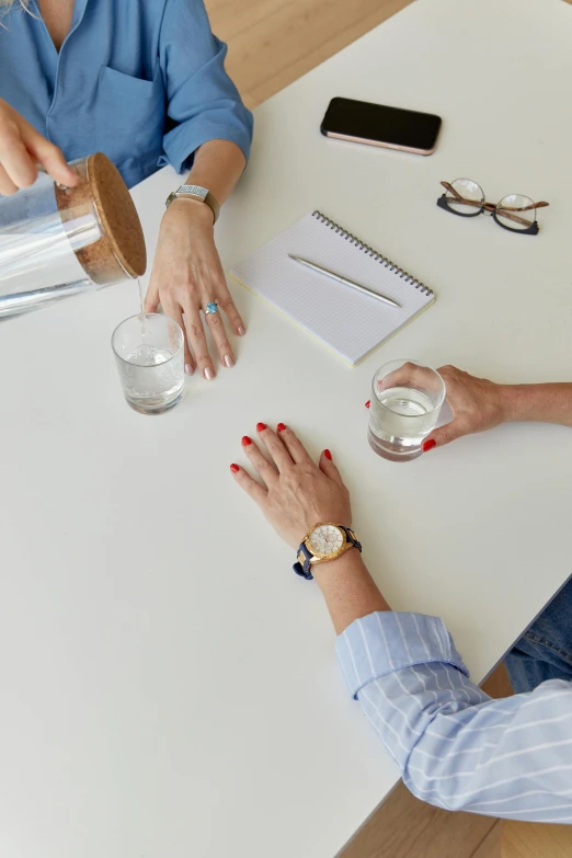 a couple of people that are sitting at a table, sleek hands, filling with water, in an office, curated collections