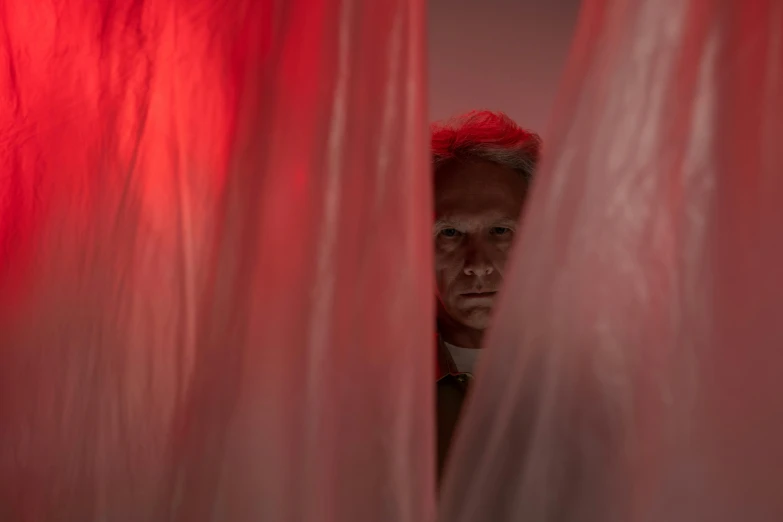 a man standing in front of a red curtain, claustrophobic, silver red, silk tarps hanging, up-close
