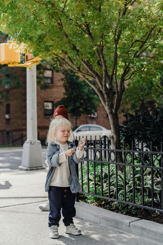 a little girl riding a skateboard down a sidewalk, by Ellen Gallagher, trending on unsplash, in the middle of new york, hold up smartphone, blond boy, gardening