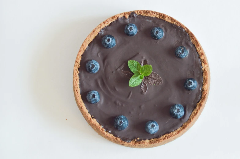 a chocolate tart topped with blueberries and mint leaves, a pastel, by Robbie Trevino, pexels contest winner, hurufiyya, 5k, full front view, 4k serene, shot on sony a 7