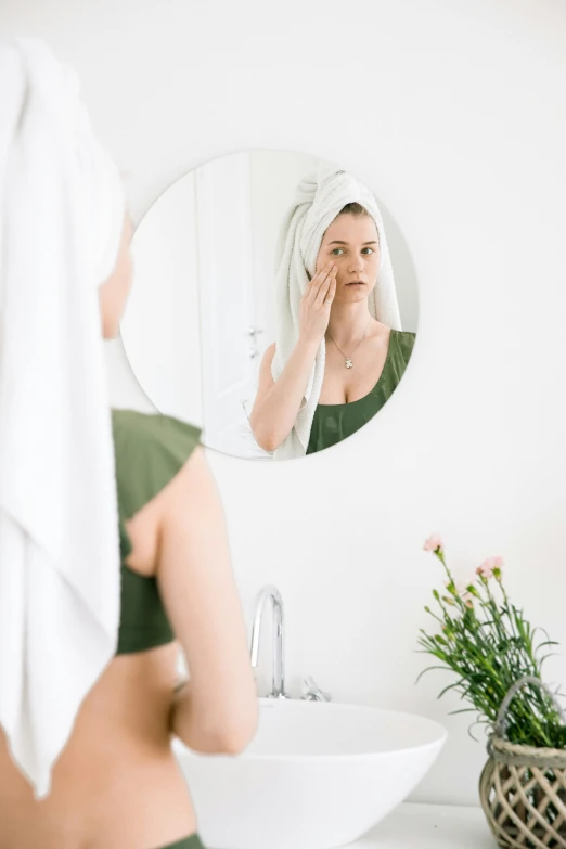 a woman standing in front of a mirror brushing her teeth, a picture, by Nicolette Macnamara, trending on pexels, renaissance, green facemask, manuka, sleepy fashion model face, wearing a towel