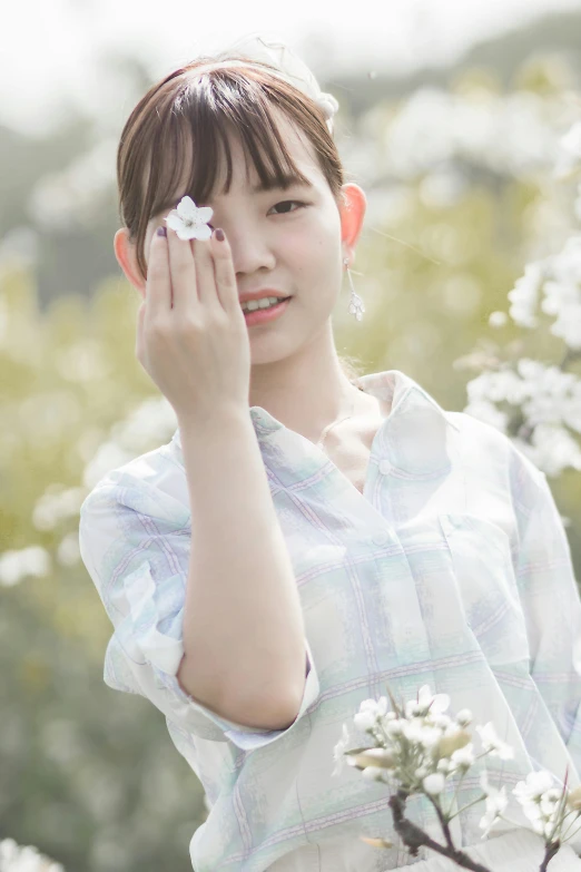 a woman holding a flower in front of her face, by Ai-Mitsu, unsplash, shin hanga, wearing a light shirt, white!!, iu, 🌸 🌼 💮