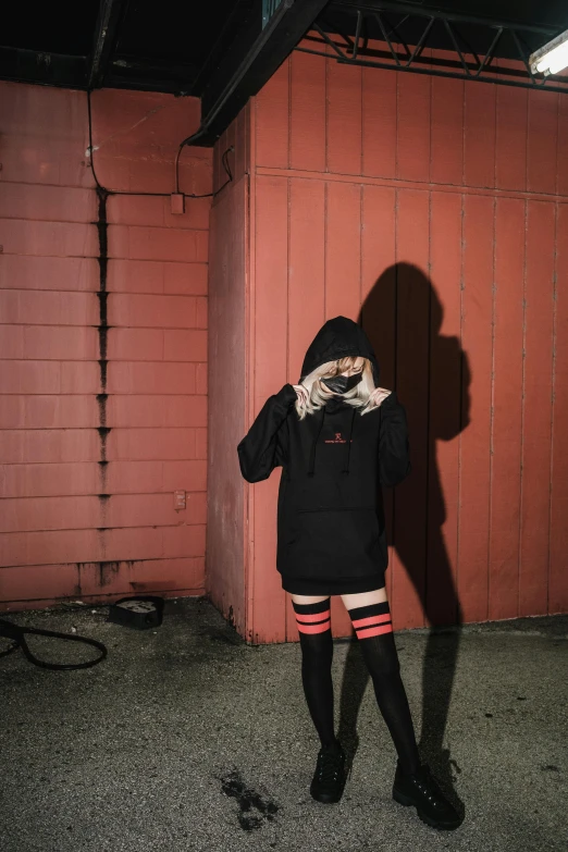 a person standing in a garage talking on a cell phone, an album cover, inspired by Elsa Bleda, unsplash, aestheticism, red and black cape and hoodie, thighs thighs thighs thighs, red eyed, japanese streetwear