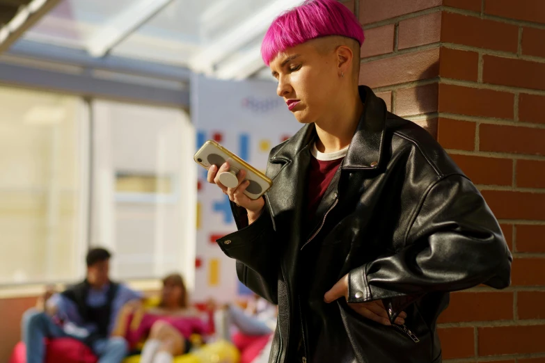 a woman with pink hair standing next to a brick wall, looking at his phone, school class, nonbinary model, performing