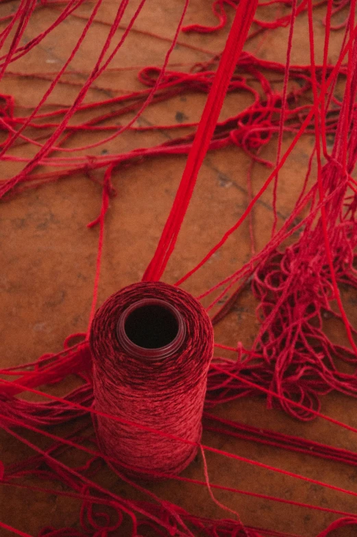 a pile of red yarn sitting on top of a wooden floor, inspired by Chiharu Shiota, unsplash, spirals tubes roots, made of silk paper, woven with electricity, mesh roots. closeup