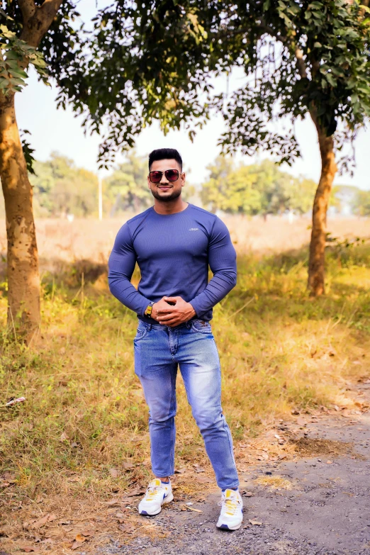 a man standing in the middle of a dirt road, by Rajesh Soni, blue tight tshirt, big wide broad strong physique |, indoor picture, autumn season