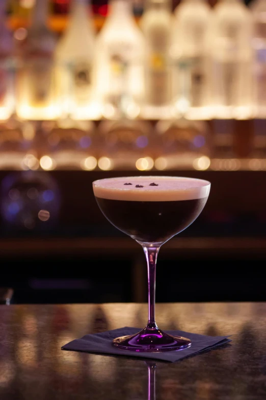 a close up of a drink in a glass on a table, inspired by Ndoc Martini, black and purple, cappuccino, midnight, bar