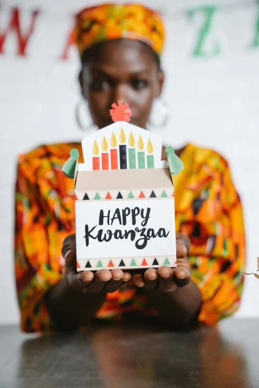 a woman holding a cake with candles on it, an album cover, by Ingrida Kadaka, trending on unsplash, hurufiyya, wearing an african dress, paper craft, close up front view, happy people