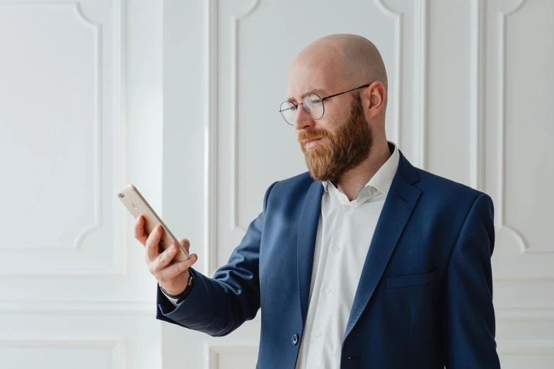 a bald man in a blue suit holding a cell phone, pexels contest winner, ginger bearded man with glasses, profile image, white man, norwegian man