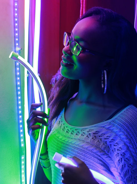 a woman standing in front of a neon light, muted rainbow tubing, ( ( dark skin ) ), brandon woelfel, having fun. vibrant