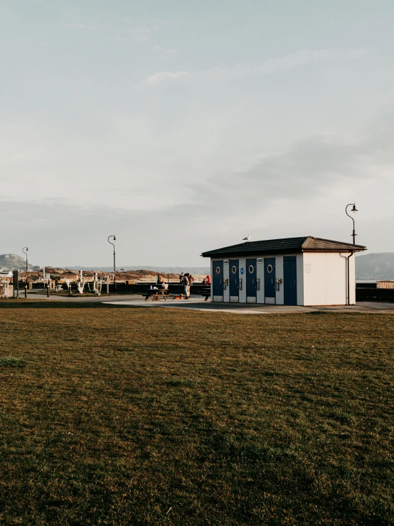 a man flying a kite on top of a lush green field, a picture, by Niko Henrichon, unsplash contest winner, small buildings, next to the sea, 🚿🗝📝, people resting on the grass