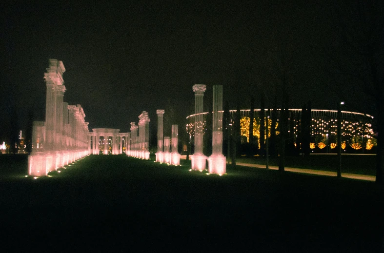 a fountain lit up at night in front of a building, inspired by Carel Willink, pexels contest winner, neoclassicism, colonnade, cai guo-qiang, photo 1998, festival. scenic view at night