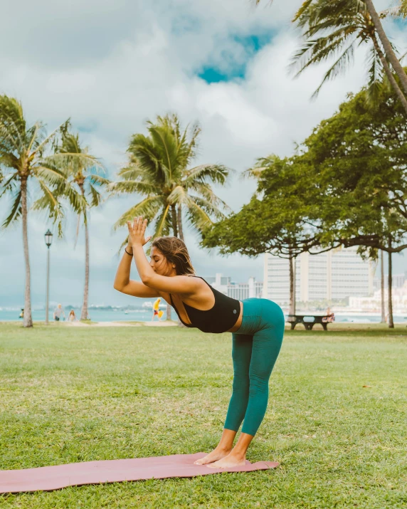 a woman doing a yoga pose in a park, by Rachel Reckitt, pexels contest winner, waikiki beach, lawn, arched back, low quality photo