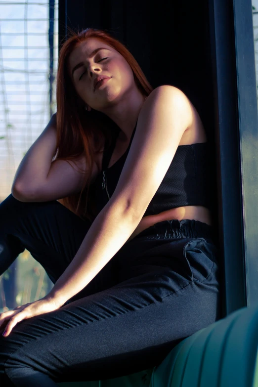 a woman sitting on a window sill with her eyes closed, inspired by Elsa Bleda, trending on pexels, renaissance, wearing a cropped black tank top, pants, a redheaded young woman, wearing black stylish clothing