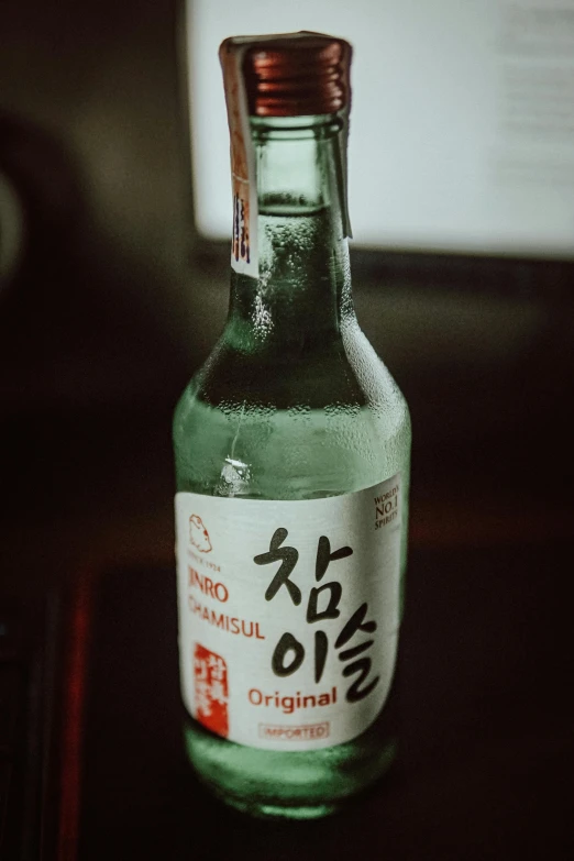 a bottle of water sitting on top of a table, a picture, inspired by Kanō Shōsenin, unsplash, beer bottle, she is korean, a labeled, mid night