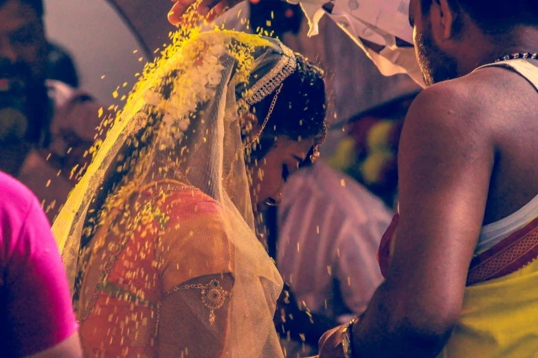 a man pouring yellow powder on a woman's face, pexels, dressed in a sari, wearing a wedding dress, banner, slightly pixelated