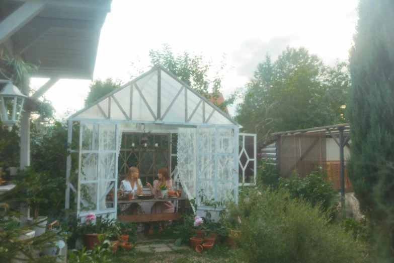 a couple of people sitting at a table in a garden, green house, slavic style, low quality photograph, cottagecore!!