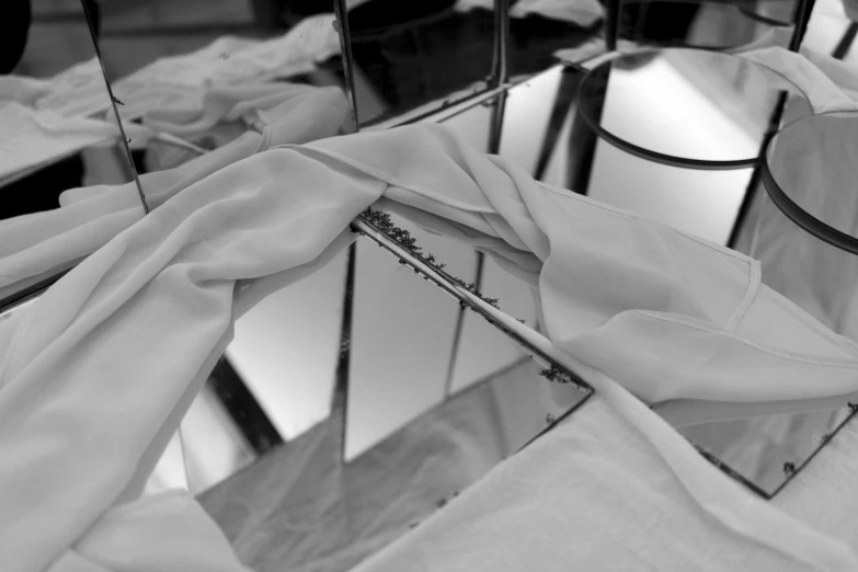 a black and white photo of a mirror with a cloth draped over it, process art, tables, steel plating, closeup, white clothes