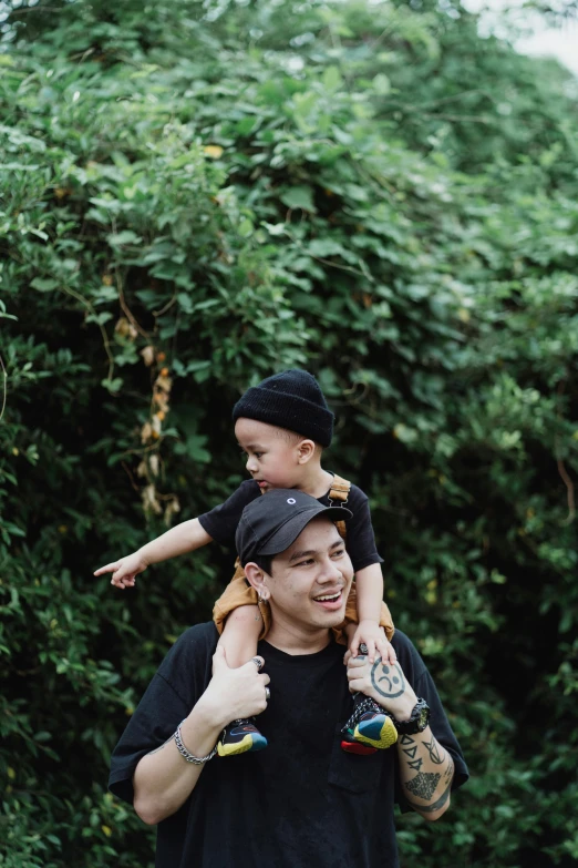 a man carrying a child on his shoulders, by Basuki Abdullah, unsplash, realism, amongst foliage, black canvas, slightly smiling, toys