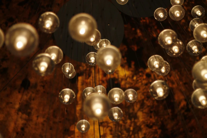 a bunch of lights that are in the air, an album cover, inspired by Bruce Munro, pexels, baroque, brown atmospheric lighting, some spherical, cafe lighting, shot from below